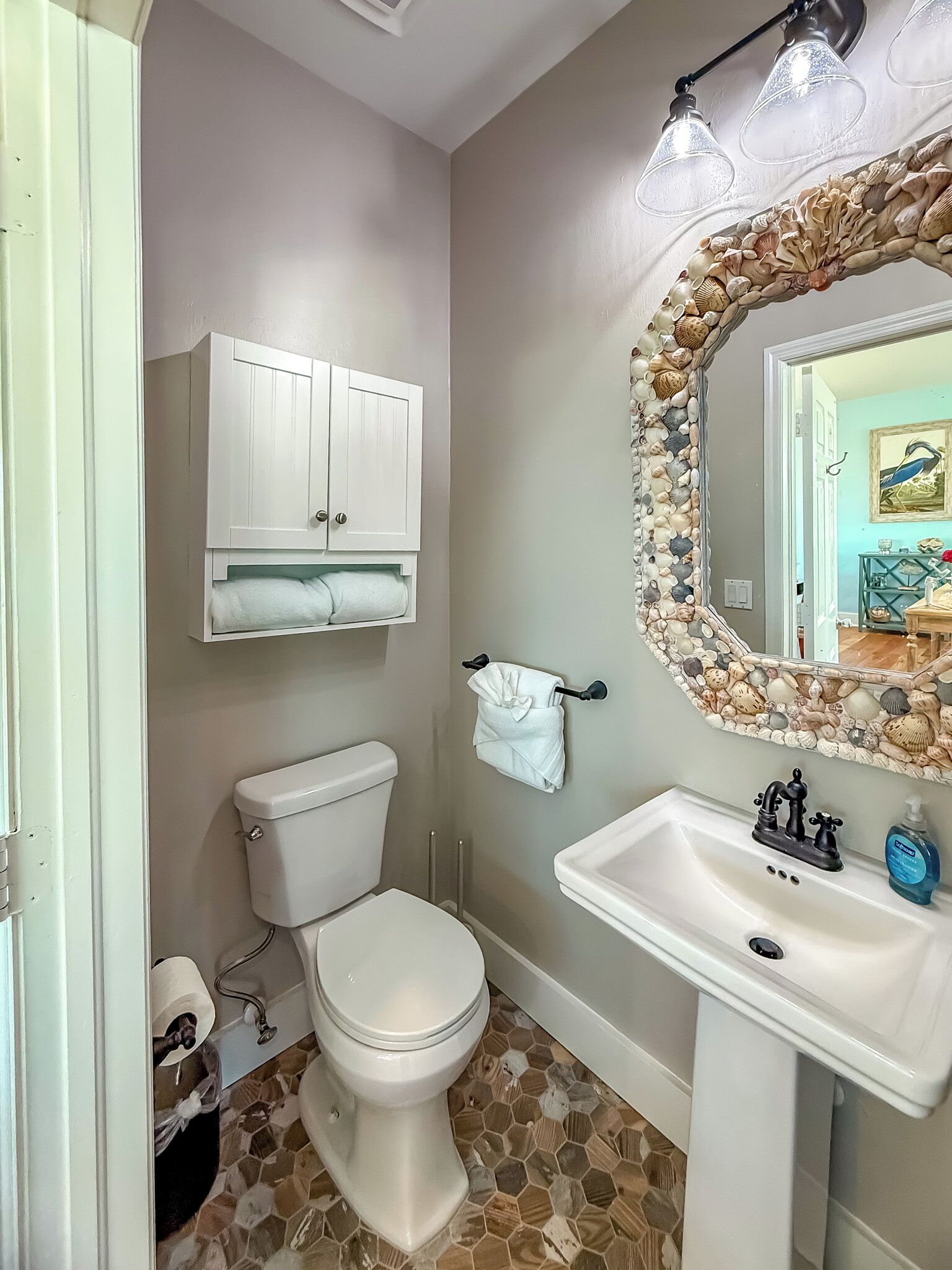Un bagno con il water, un lavandino, uno specchio con cornice a conchiglia e un porta asciugamani.