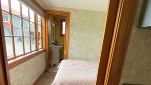 Ein Schlafzimmer mit Bett, Fenster, Waschbecken und Spiegel.