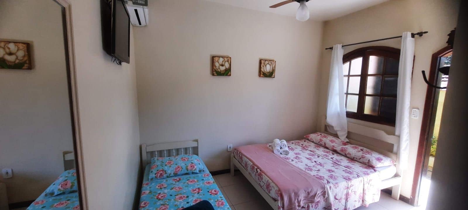 A bedroom with two single beds, a ceiling fan, and a window with curtains.