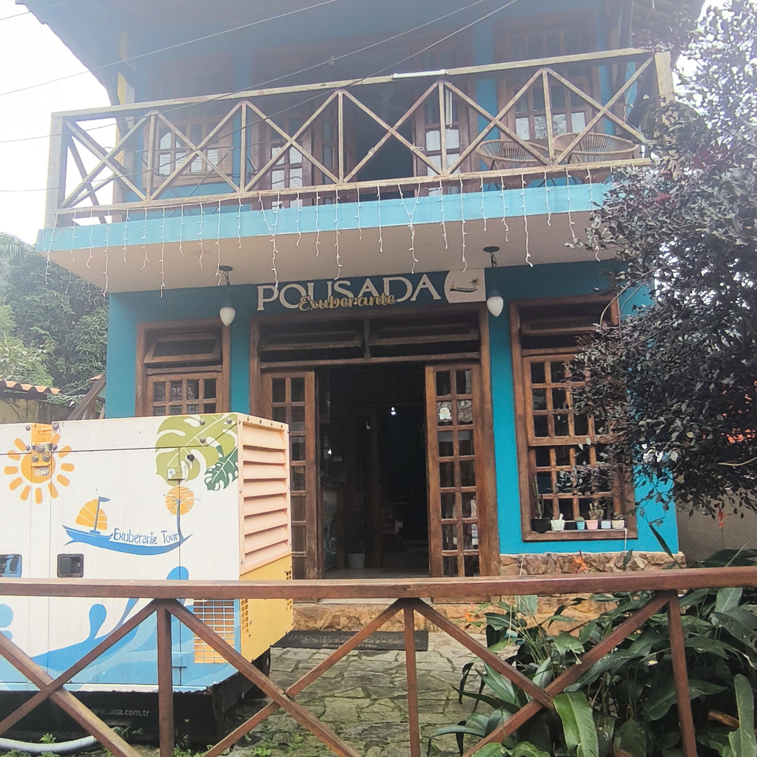 A two-story building with a balcony, a sign reading 'POLISADA,' and a colorful mural on the side.