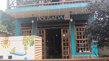 A two-story building with a balcony, a sign reading 'POLISADA,' and a colorful mural on the side.