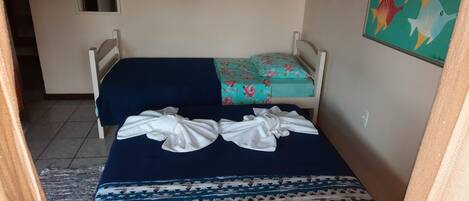 Una habitación pequeña con una cama individual, una colcha azul y un cojín estampado con motivos florales.