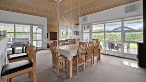 A spacious dining area with wooden furniture and large windows offering views of the outdoors. - Nice home in Tarm with sauna (Tarm)
