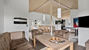 A spacious living area with a high ceiling, a dining table with chairs, a sofa, and a kitchen area in the background. - Nice home in Tarm with sauna (Tarm)