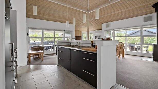 A modern kitchen with large windows, a dining area, and a view of the outdoors. - Nice home in Tarm with sauna (Tarm)