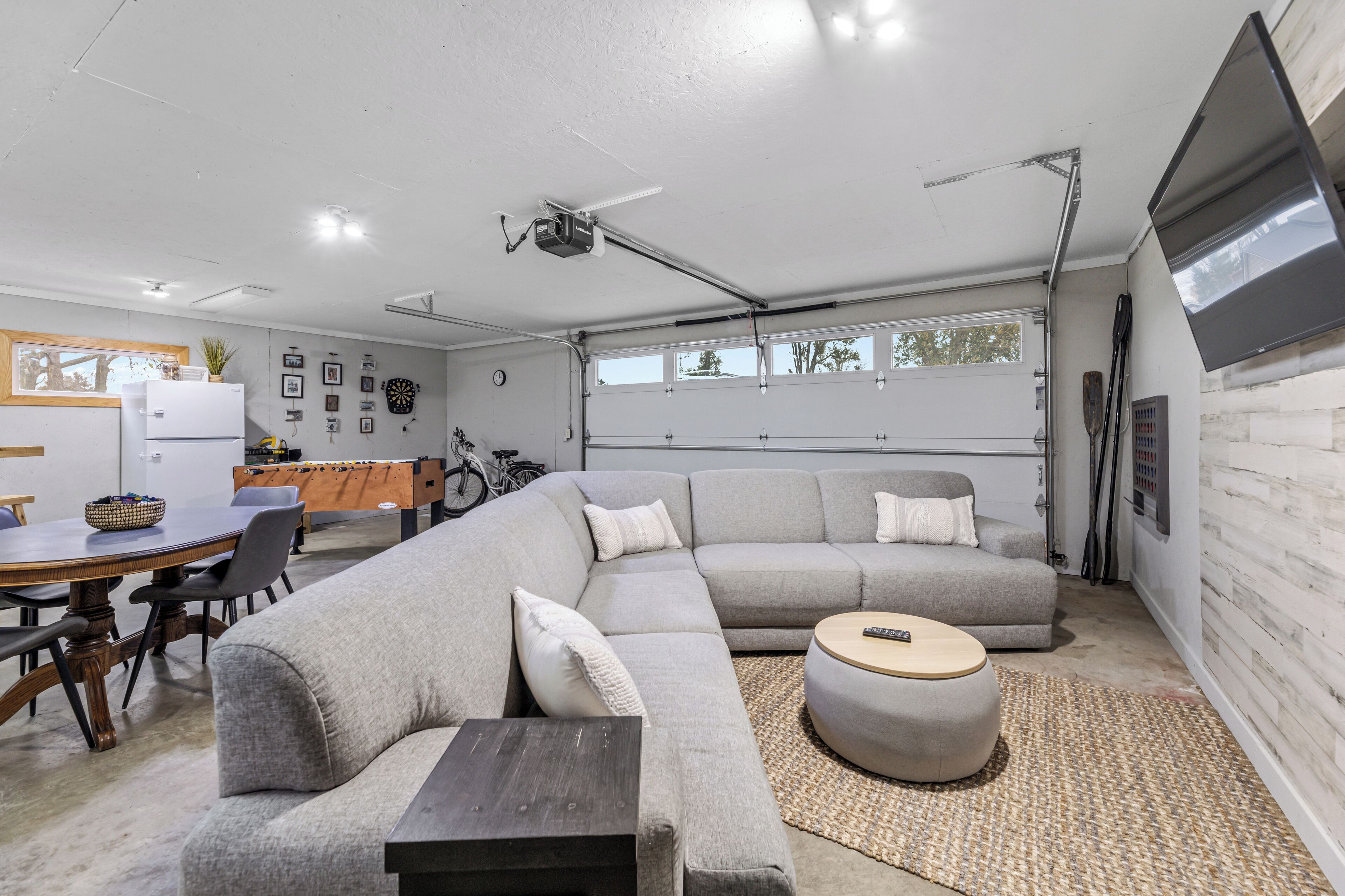 A modern living room with a sectional sofa, a round coffee table, and a dining area with a table and chairs.