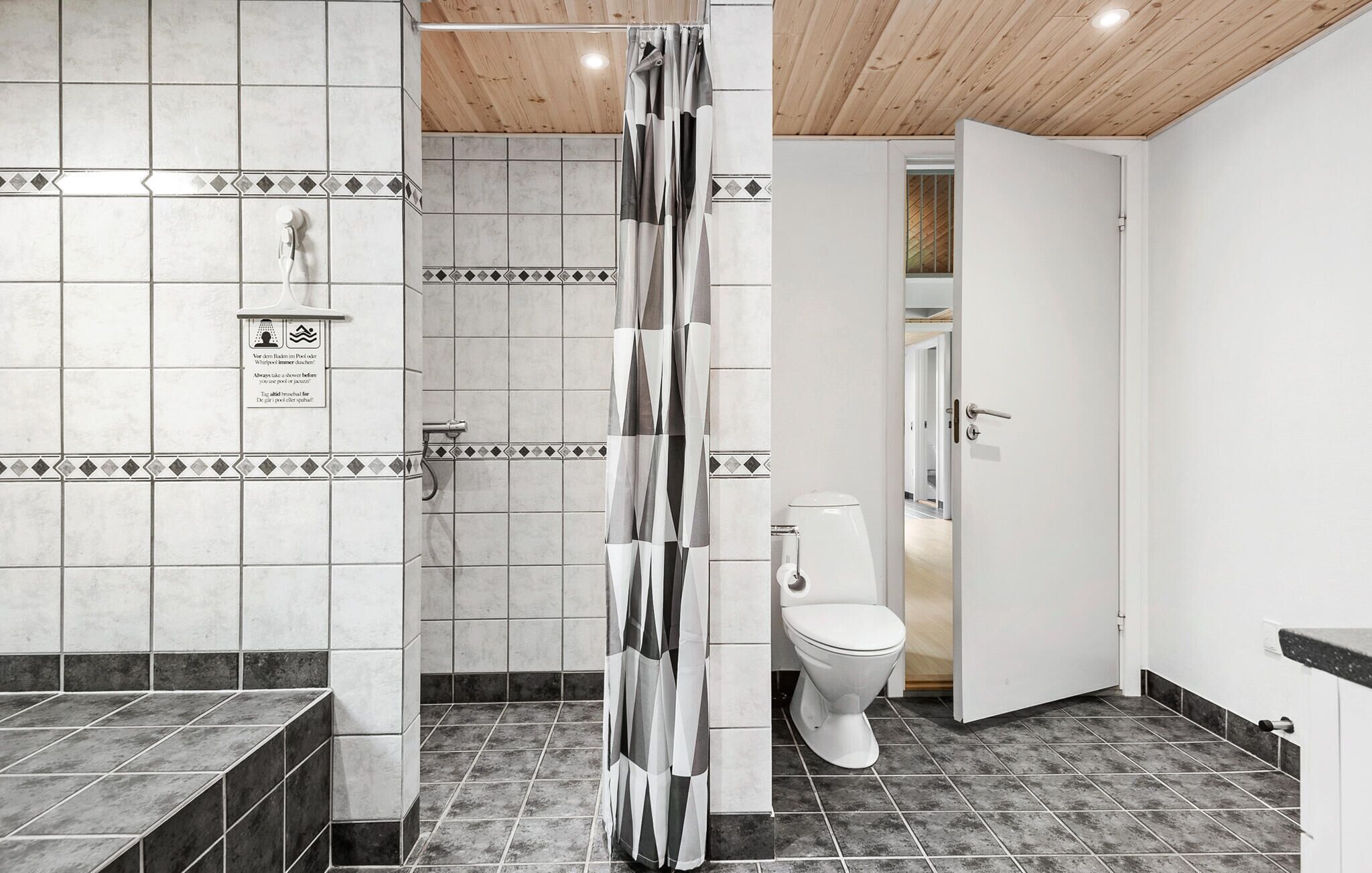 A modern bathroom with a shower, toilet, and a sign on the wall.