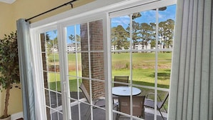 A room with a sliding glass door leading to an outdoor patio with a table and chairs. - Cozy Ground Floor 3BR Condo at Myrtlewood Golf (Myrtle Beach)