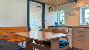 Una cocina compacta con una mesa y sillas de madera, un reloj en la pared y una ventana que proporciona luz natural.
