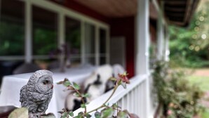 Een veranda met een witte balustrade en een vogelbeeld.