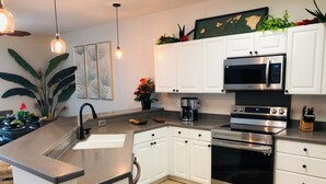 A modern kitchen with white cabinets, stainless steel appliances, and a granite countertop.