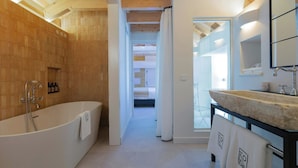 Un baño moderno con una bañera independiente, un espejo grande y un lavabo de piedra.