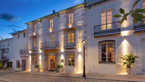 Un edificio de varios pisos con balcones, una farola y plantas en macetas.