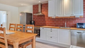 A modern kitchen with white cabinets, a brick backsplash, and stainless steel appliances. - 3 bedroom gorgeous home in Floby (Floby)