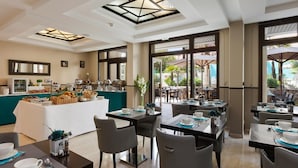 A modern dining area with a buffet, tables set for dining, and a view of the outdoor patio. - Bright Pool View Room in Cannes (Cannes)