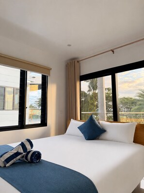 Une chambre d’hôtel avec un lit, une fenêtre avec des rideaux et une vue sur la verdure.