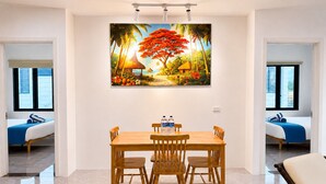 Un comedor con una mesa y sillas de madera, un cuadro en la pared y vistas a través de una puerta abierta.