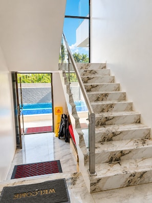 A marble staircase leading to a pool area with a view of greenery outside. - My Wailoaloa Apartment (Nadi)