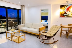A modern living room with a sofa, a rocking chair, a coffee table, and a dining area.