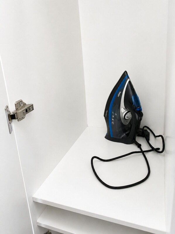 A white door with a silver handle and a black and blue iron on a white shelf.