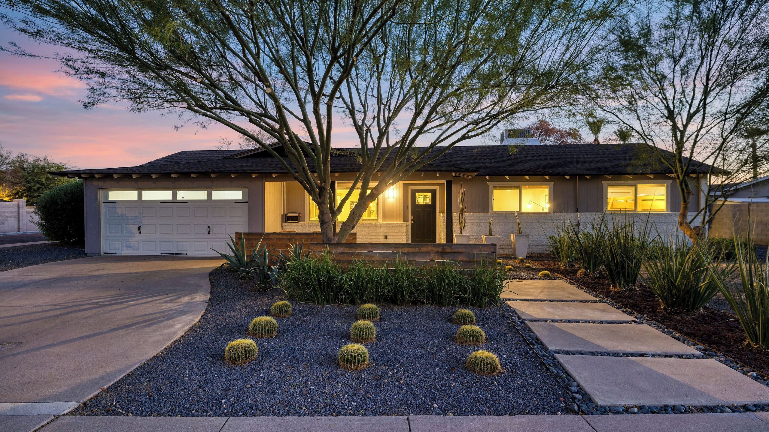 A residential house with a garage, a front porch, and a landscaped garden with cacti.