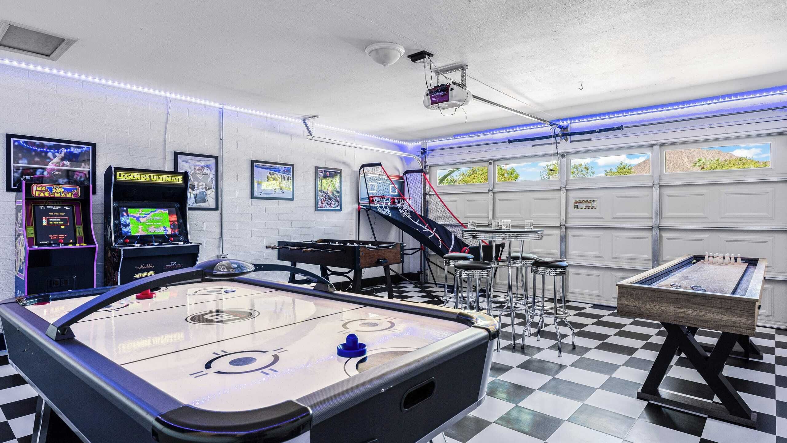 A recreational room with an air hockey table, arcade games, and a pool table.