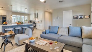 A modern living room with a grey sofa, a coffee table with a chessboard, and a bar area with stools. - Near Camelback Mtn, Old Town, Trails, Golf + Spas w/ Pool, Hot Tub Camelback Casa by Avantstay (Phoenix)
