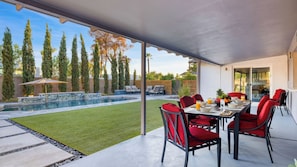 A covered patio with a pool, red chairs, and a dining table. - Near Camelback Mtn, Old Town, Trails, Golf + Spas w/ Pool, Hot Tub Camelback Casa by Avantstay (Phoenix)
