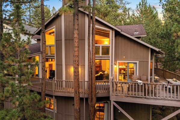 Une cabane en bois à plusieurs étages, dotée de grandes fenêtres, d’une terrasse et d’un coin repas.
