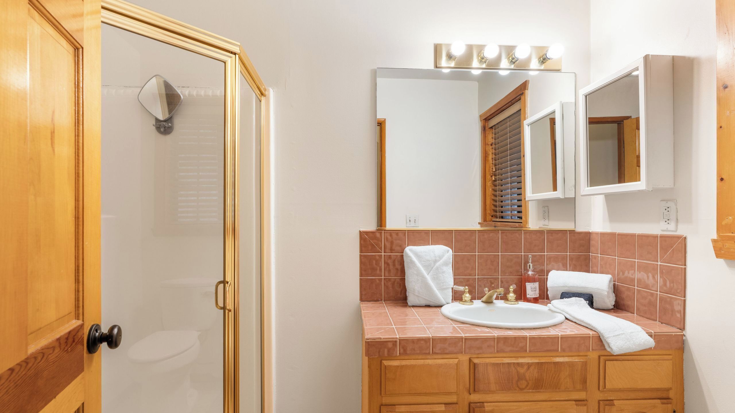 Une salle de bain équipée d’une douche, d’un lavabo, d’un miroir et d’un meuble-lavabo avec une serviette.