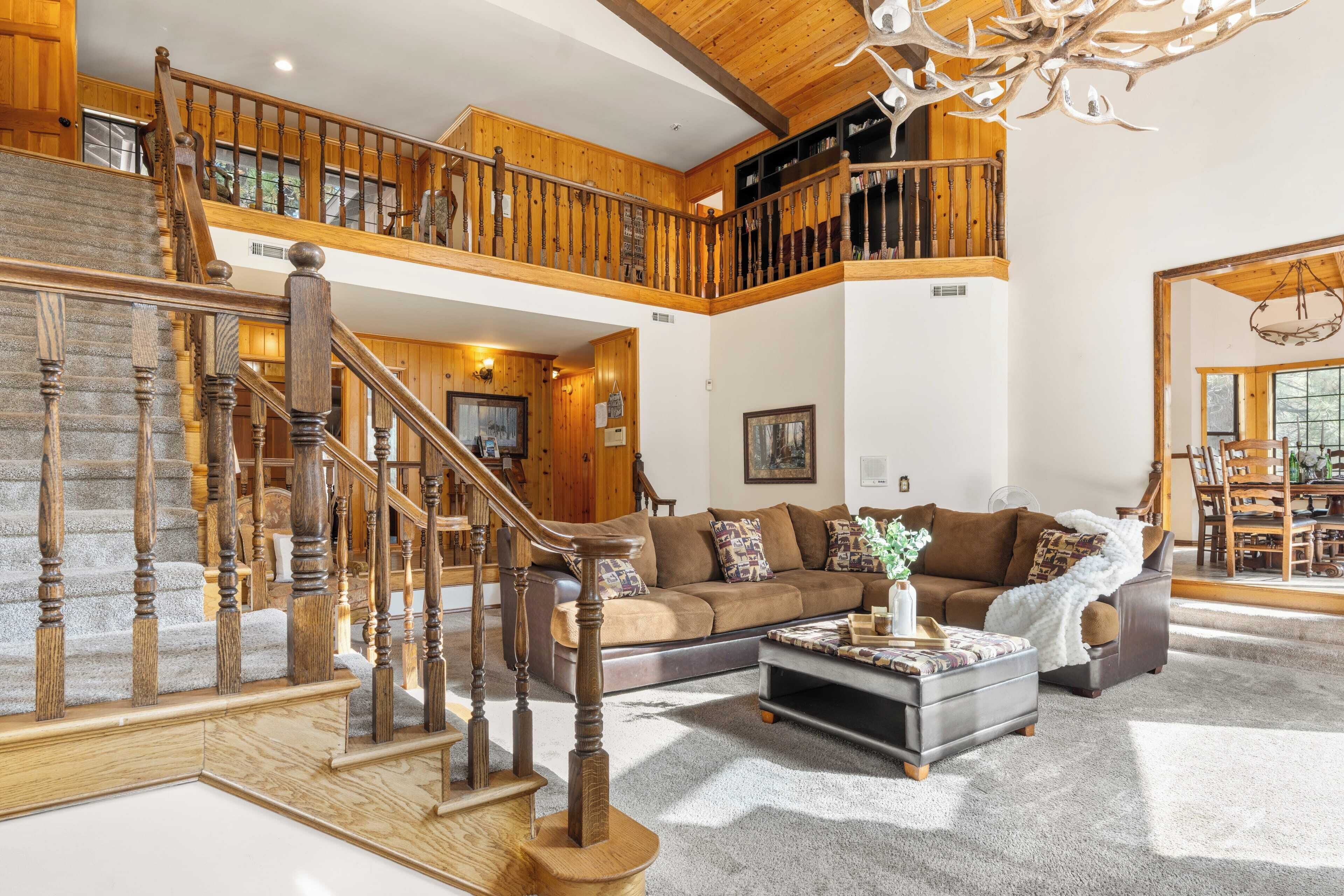 Ein geräumiger Wohnbereich mit einer Holztreppe, einem großen Sofa und einem Essbereich.
