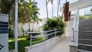A staircase leading to a building with a glass entrance, surrounded by greenery and palm trees. - 1-bedroom Apartment 850 m From Masc - Cfe0503 (Florianópolis)