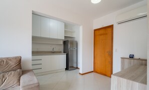 A modern kitchen with white cabinets, a stainless steel refrigerator, and a wooden door. - 1-bedroom Apartment 850 m From Masc - Cfe0503 (Florianópolis)