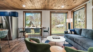 Una cocina moderna con un refrigerador de acero inoxidable, techo de madera y ventanas amplias con vistas al exterior.