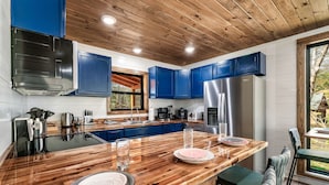 Una cocina moderna con armarios azules, techo de madera y una isla grande con asientos.