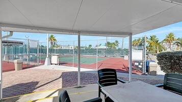 Un espace extérieur aménagé avec des courts de tennis, des sièges et un pavillon couvert.