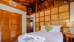 Een slaapkamer met een groot bed, een houten garderobe en een hoofdeinde van bamboe.