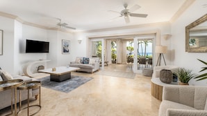 A spacious living room with a flat-screen TV, a ceiling fan, and a view of the outdoors.