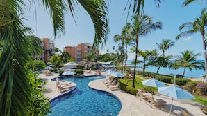 A resort pool area with lounge chairs, umbrellas, and a clear view of the ocean. - Beachfront Family Retreat - Saint Peter's Bay 111 (2 bed) (Battaleys)