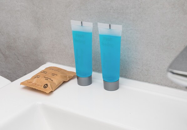 Two blue water bottles on a white sink with a brown paper bag beside them.