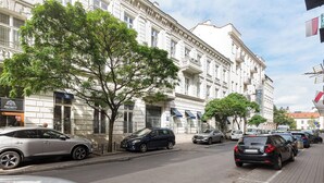 Una calle con coches aparcados y un edificio con balcones.
