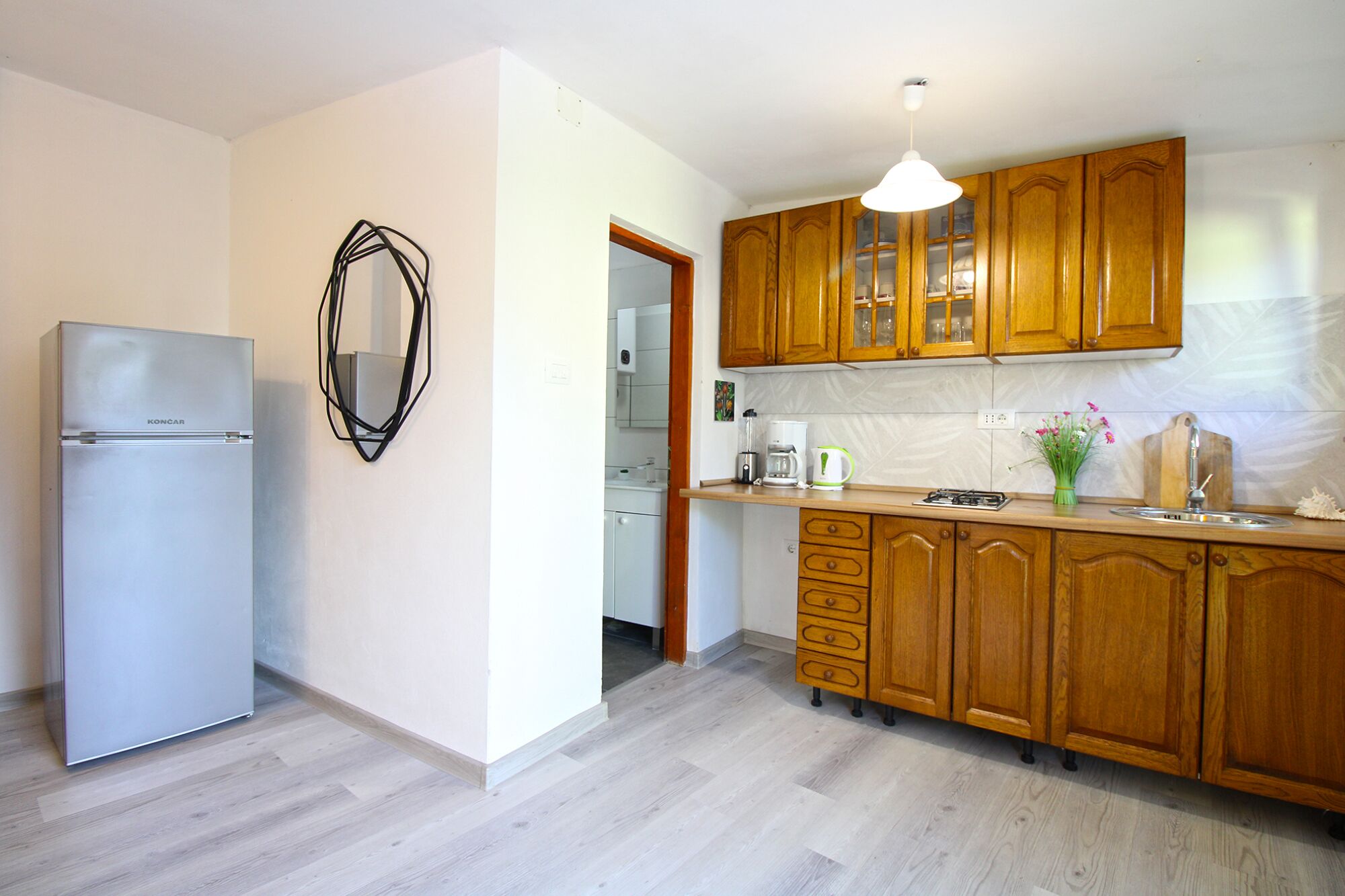 Une cuisine moderne avec des meubles en bois, un réfrigérateur en acier inoxydable et un four encastré.