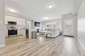 A spacious living area with a kitchen, a dining area, and a seating area with a sofa and a coffee table. - The Devineridge Executive House (Ajax)