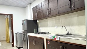 A kitchen with dark cabinets, a refrigerator, a sink, and a stove. - Cozy apartment (Leticia)