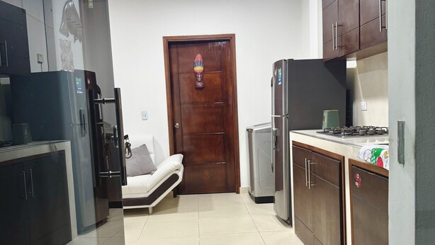 A kitchen with a sofa, cabinets, and a door with a decorative item. - Cozy apartment (Leticia)