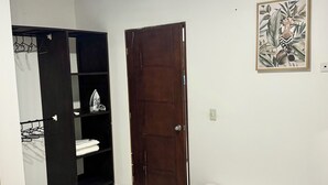 A bedroom with a bed, a wardrobe, a door, and a wall-mounted picture. - Cozy apartment (Leticia)