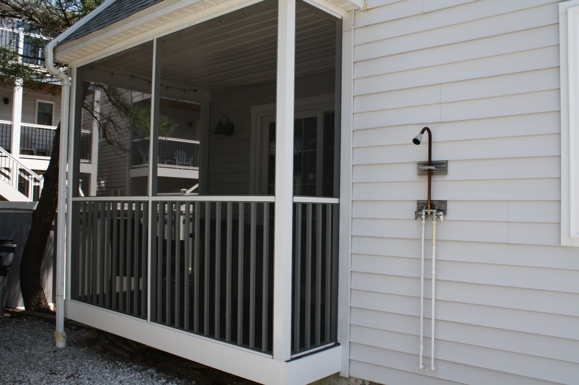 A covered porch with a railing, a window, and a wall-mounted shower.