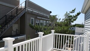 Un immeuble résidentiel avec un balcon blanc, un escalier et un arbre en arrière-plan.