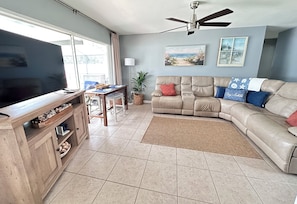 A living room with a television, a sofa, a coffee table, and a ceiling fan.