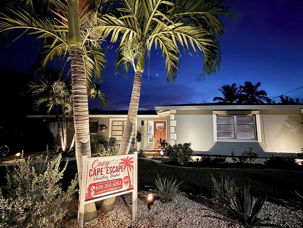A vacation rental property with a sign advertising 'Cozy Cape Escape Rental.'